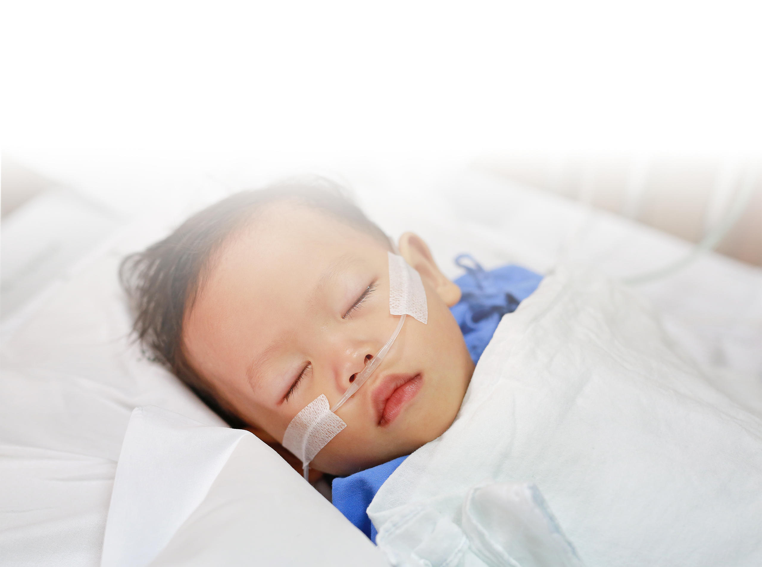 young child laying in a hospital bed with a white blanket over his chest and a nasal cannula in his nose for noninvasive ventilation